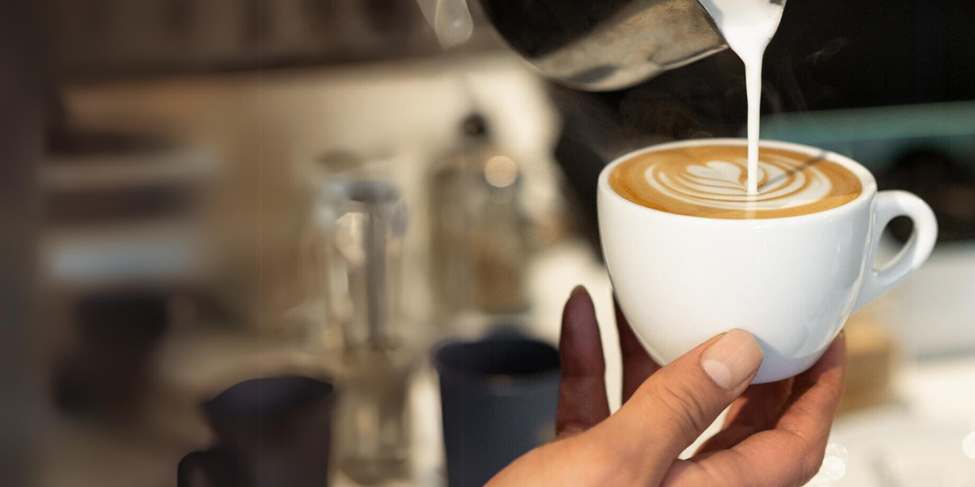 Steamed milk poured into a cup of espresso creating a latte art pattern.
