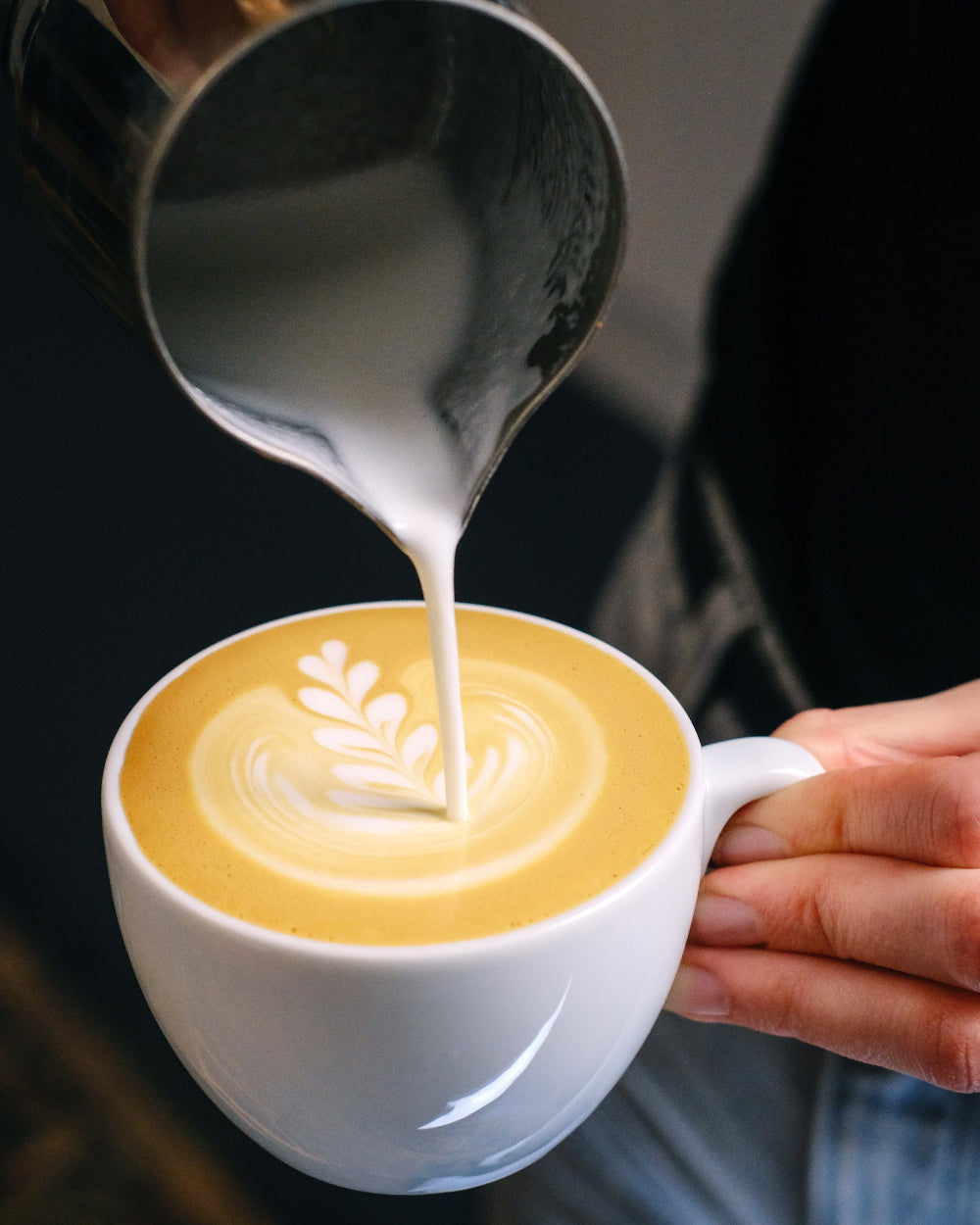 Steamed milk poured into a cup of coffee during a latte art workshop.